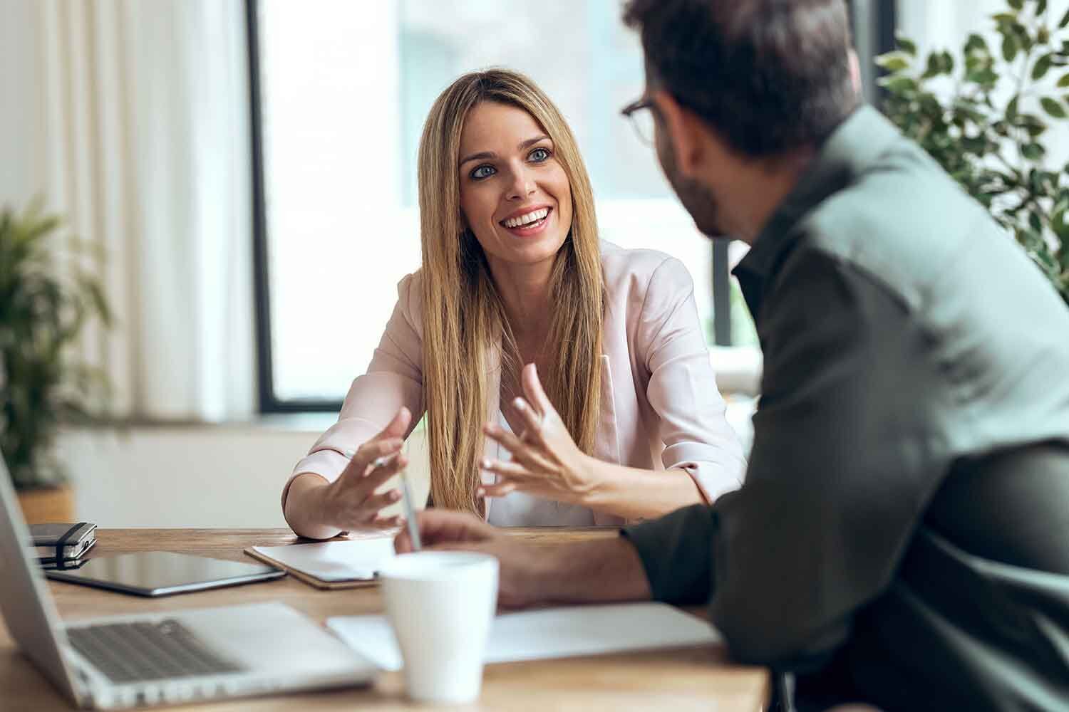 eine Frau und ein Mann, die an einem Tisch sitzen und reden